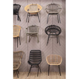 A collection of various rattan chairs displayed on a wall, featuring different colors and styles, including a grey wash chair prominently positioned in the center. The background is neutral, enhancing the natural textures of the rattan