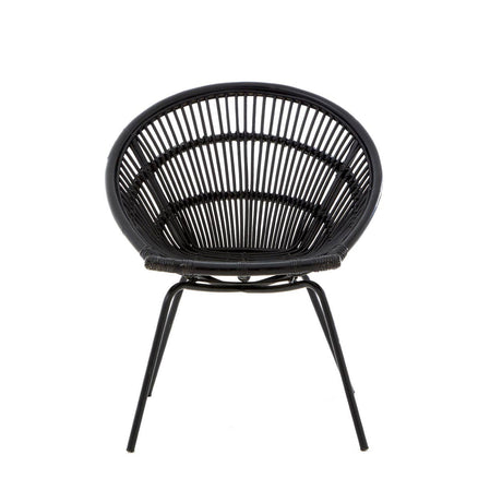 A round black rattan chair with a woven design and slender iron legs, showcasing a modern and minimalist style. The chair features a deep seat and an open back, emphasizing its airy and contemporary look