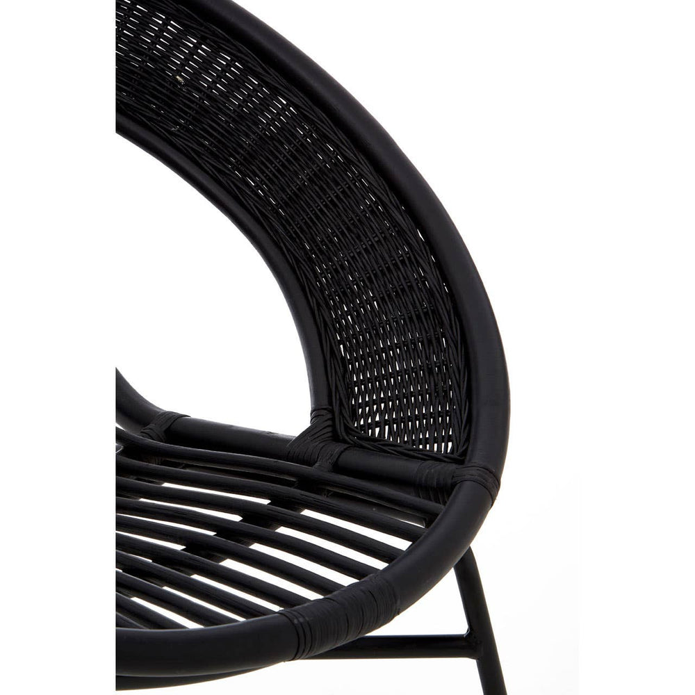 A close-up view of a black chair featuring a natural rattan seat and backrest, supported by a sleek black iron frame. The chair has a curved design with visible woven patterns in the rattan, showcasing its modern and stylish aesthetic