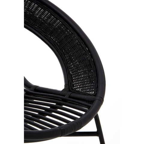 A close-up view of a black chair featuring a natural rattan seat and backrest, supported by a sleek black iron frame. The chair has a curved design with visible woven patterns in the rattan, showcasing its modern and stylish aesthetic