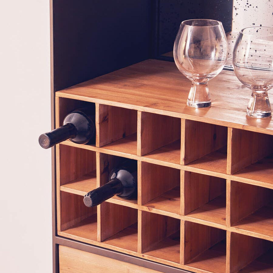 Wooden bar cabinet featuring a top section with multiple square compartments for storing bottles, two black handles, and a smooth wooden surface. A glass and decorative items are placed on top, showcasing a stylish and functional design