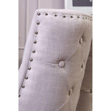Light grey upholstered dining chair with button tufting and metal stud detailing, close view