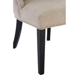 Beige upholstered dining chair with black wooden legs and silver stud detailing, close view