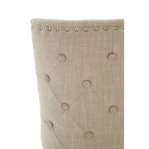 Beige upholstered dining chair back with button-tufting and metal stud trim detail