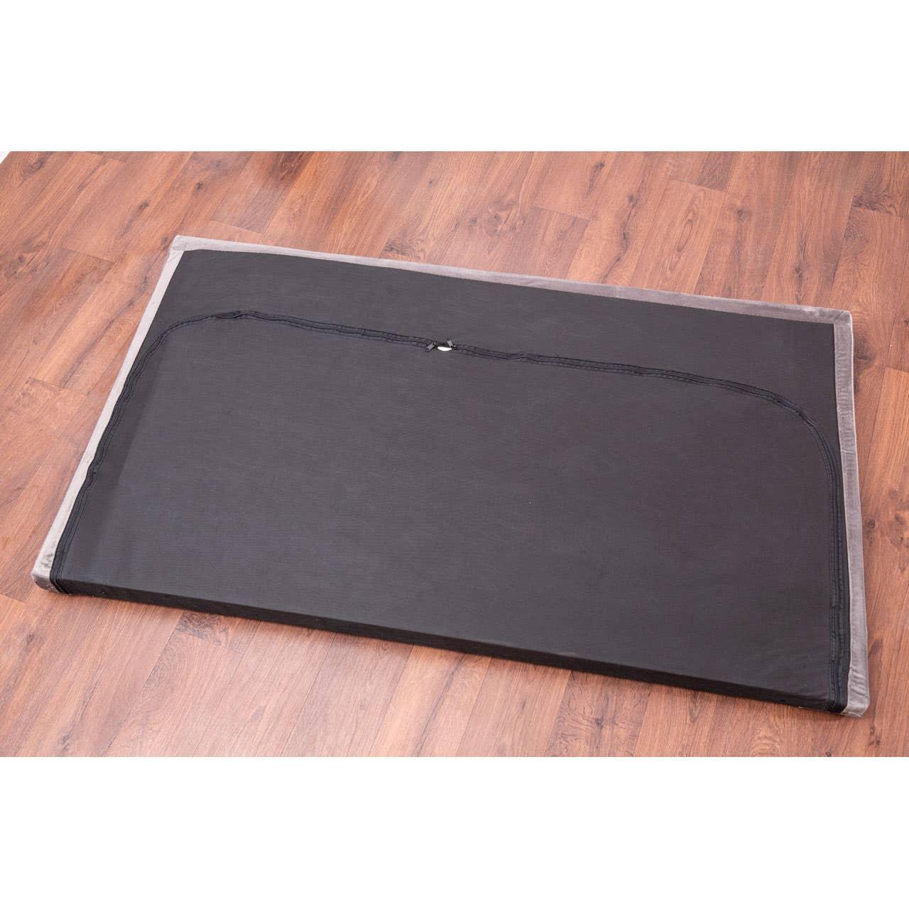 Rectangular black pet bed with grey trim on wooden floor, zipped cover visible