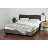 Grey upholstered bed frame with headboard, patterned bedding, and bedside table