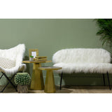A stylish two-seater sofa with a plush faux fur upholstery in white, featuring sleek black legs. The sofa is positioned next to a modern accent chair and two gold side tables, with a green wall and a potted plant in the background, creating a cozy and contemporary living space