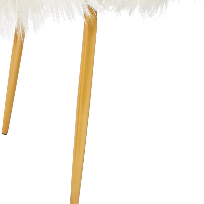 A close-up view of the legs of a white faux fur sofa, showcasing the soft texture of the upholstery and the sleek gold finish of the legs. The legs are tapered and provide a modern contrast to the plush seating