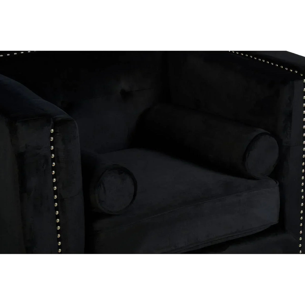 Black velvet armchair with silver stud trim and cylindrical bolster cushions