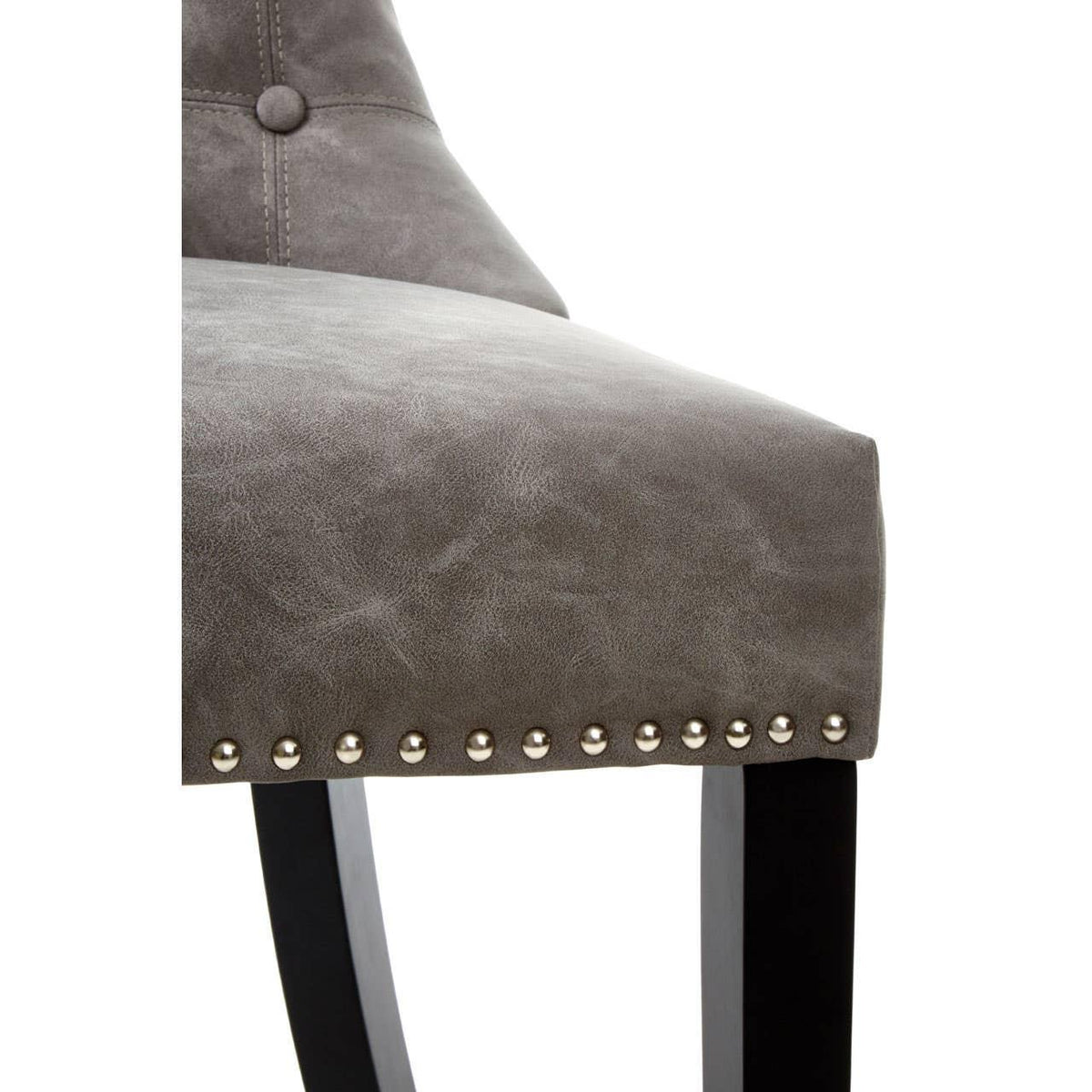 Grey dining chair close-up with button detail and metal stud trim on seat edge
