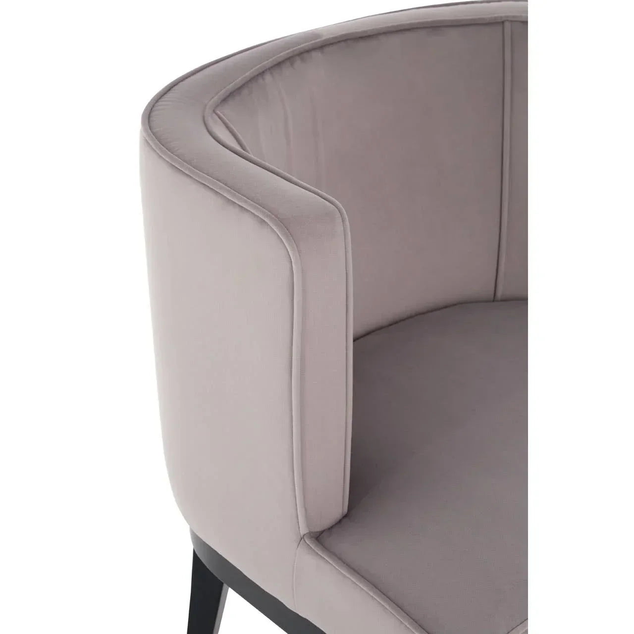 Close-up of grey velvet armchair with curved backrest and black wooden legs
