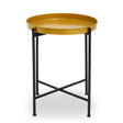 Small side table featuring a round brass top with a smooth finish, supported by a sleek black metal frame with crossbar detailing for stability. The design is modern and minimalist, suitable for various home decor styles