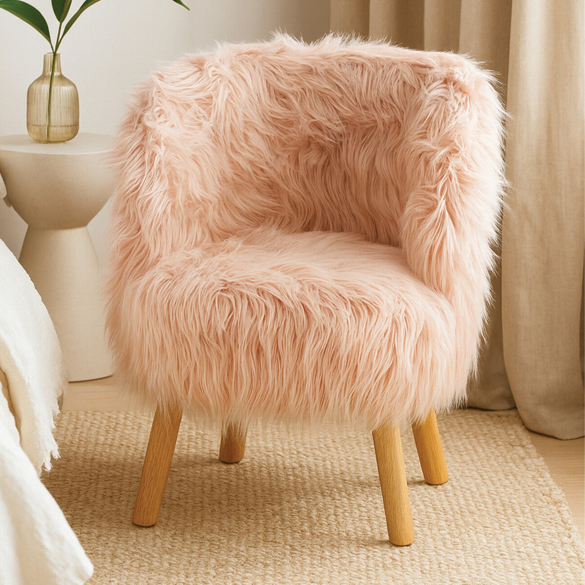 A cozy kids' chair covered in soft pink faux fur, featuring a rounded back and wooden legs, placed on a light-colored carpet with a neutral backdrop