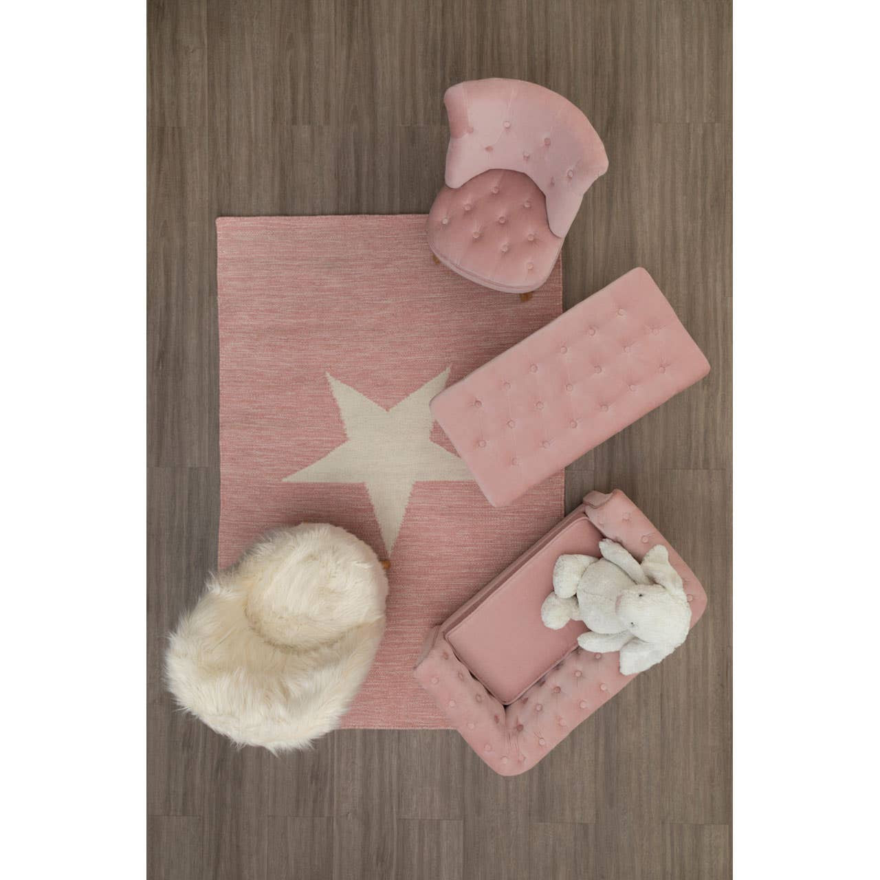A cozy kids' white faux fur chair placed on a soft pink rug featuring a star design, surrounded by a pink storage box and a fluffy white pouf, all set against a wooden floor