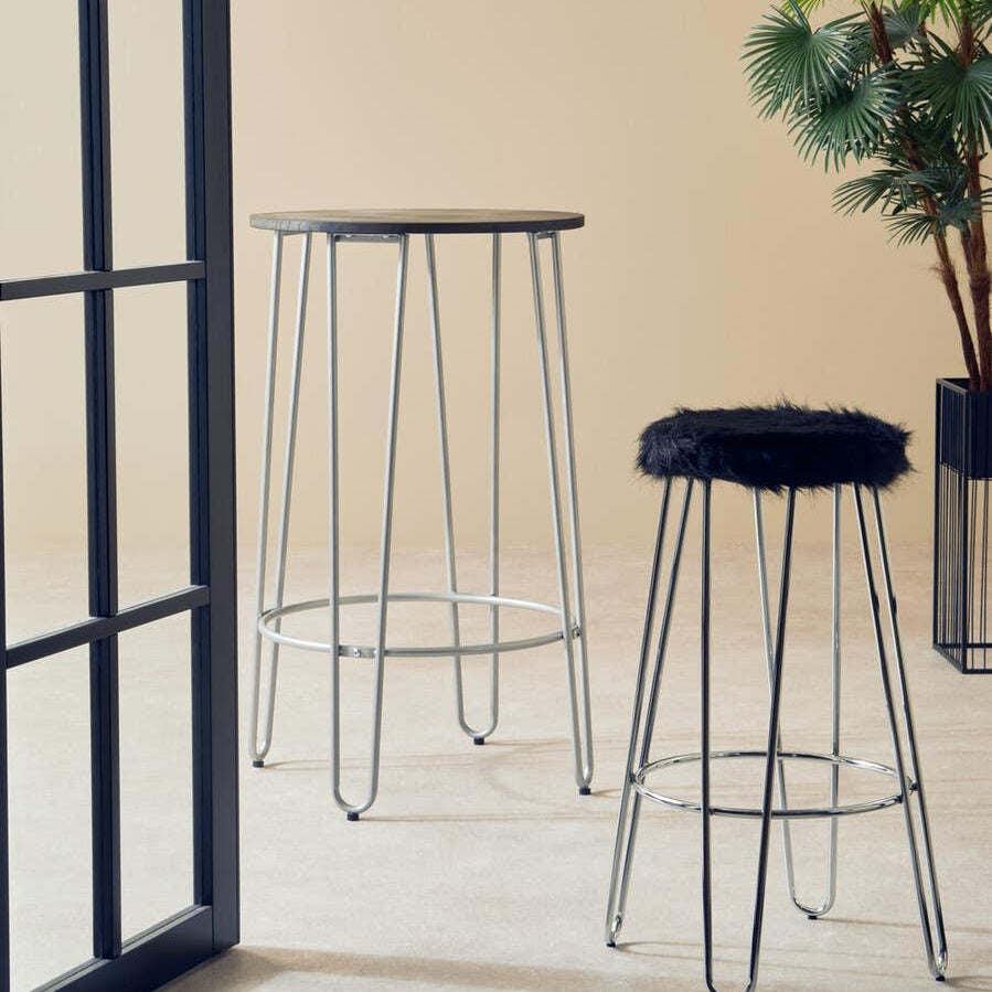 Tall bar table and fur top bar stool with chrome legs in modern indoor setting