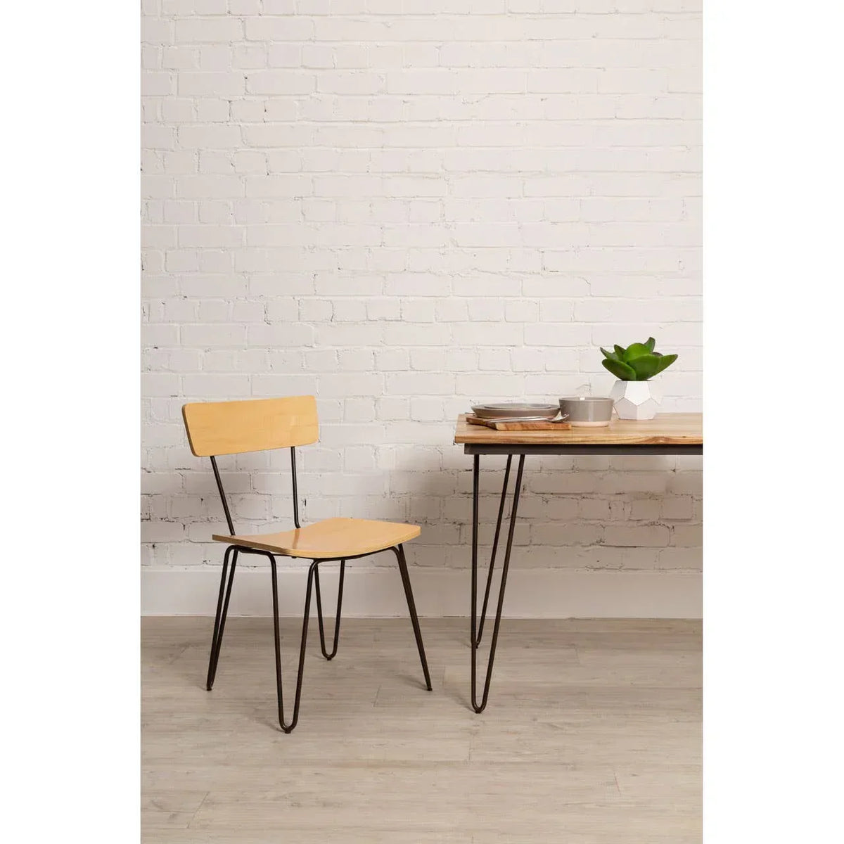 Light wood dining chair with black metal legs beside a matching table on laminate flooring