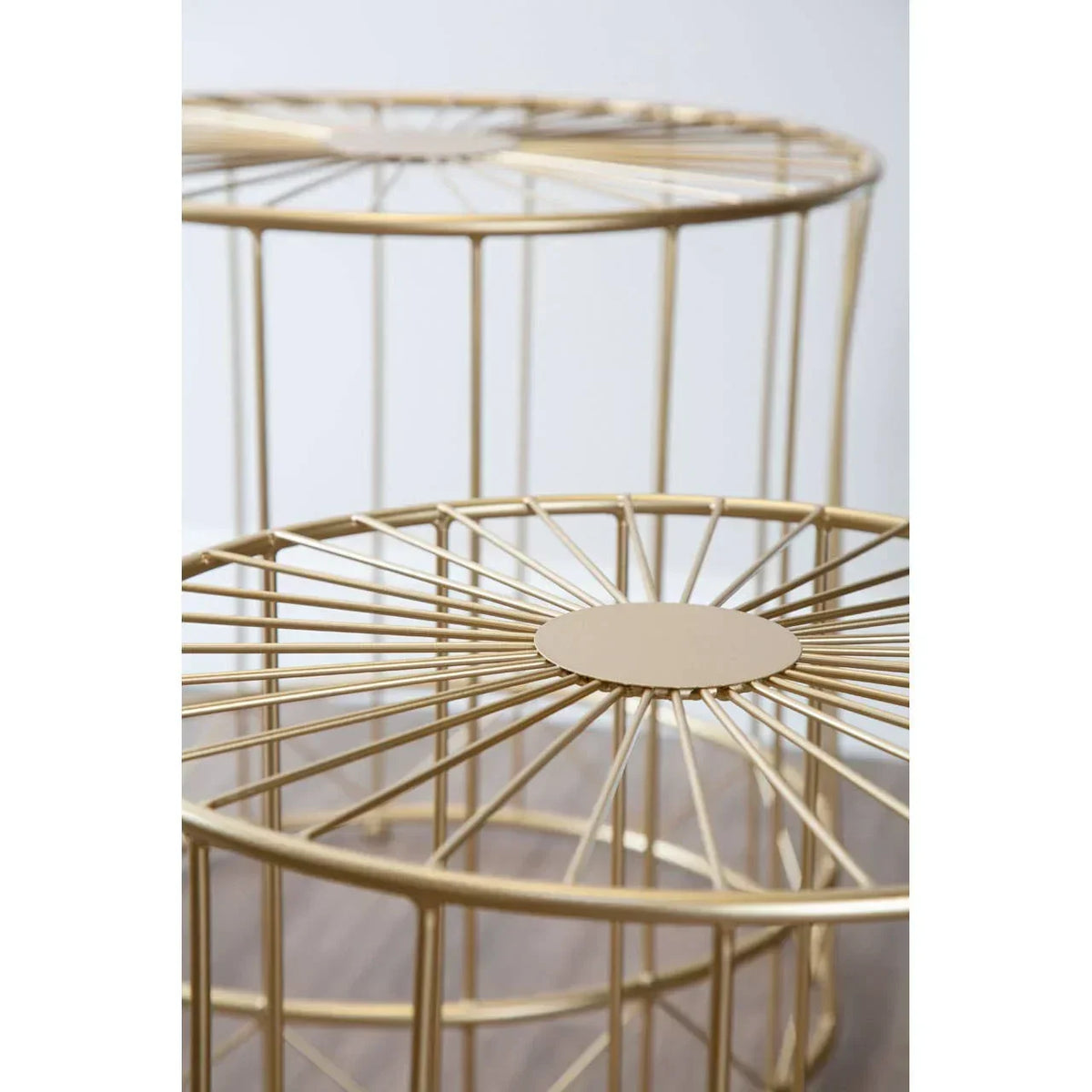 Gold metal cage side tables with round tops and open geometric frame on wood floor