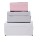 Set of three metal storage trunks in pastel pink and grey, stacked in size order