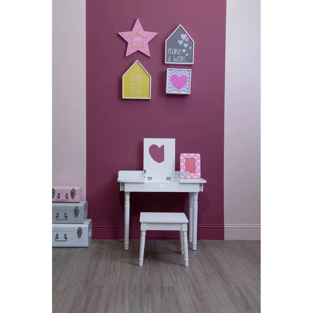 White children's dressing table with stool against pink wall, decorated with wall art and storage boxes