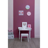 White dressing table and stool with heart mirror beside pink storage boxes on wood floor