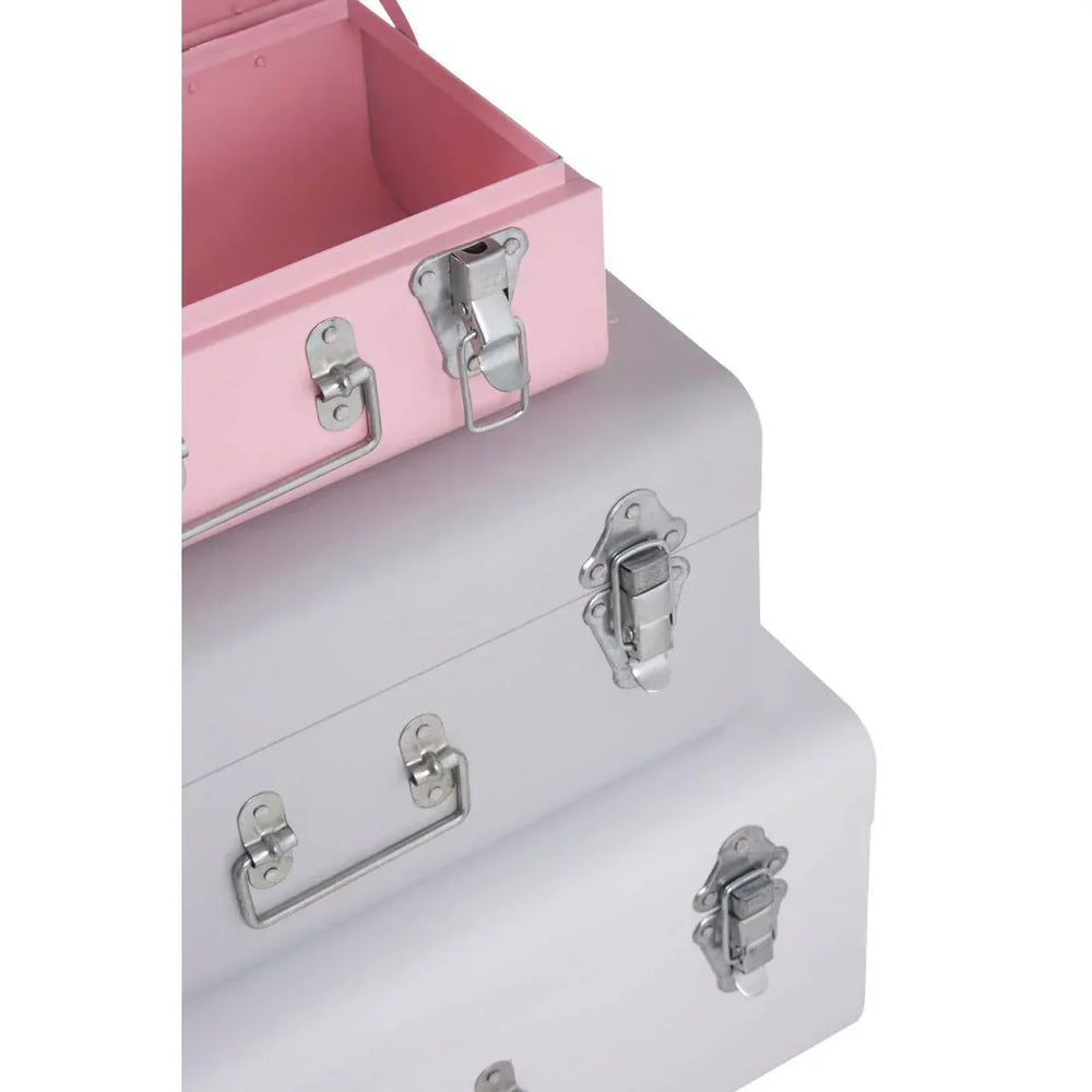 Stacked metal storage trunks in pink and grey with chrome handles and latches