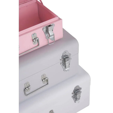 Stacked metal storage trunks in pink and grey with chrome handles and latches