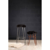 Faux fur stool with a rose gold finish, featuring a plush black seat and slender metal legs, positioned next to a taller stool against a dark wall, with a light-colored rug underneath