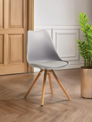 Grey dining chair with wooden legs set on herringbone wood floor next to a potted plant