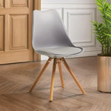 Grey dining chair with wooden legs on parquet floor beside potted plant
