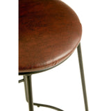 Round seat of a bar stool covered in brown faux leather, supported by sleek black metal legs. The stool features a minimalist design with a footrest for added comfort