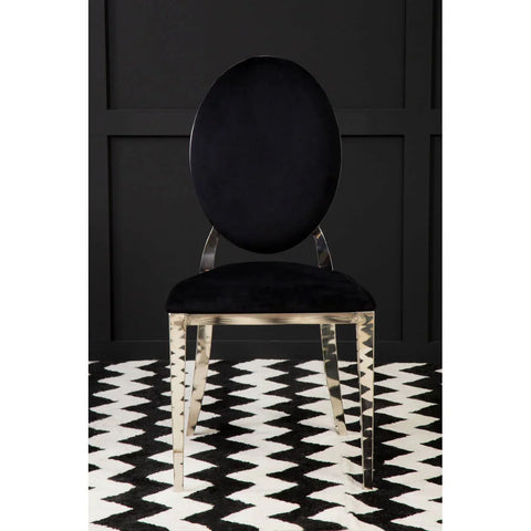Black velvet dining chair with oval back and chrome legs on patterned rug