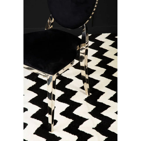 Black velvet dining chair with chrome legs on black and white zigzag patterned rug