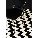 Black velvet dining chair with chrome legs on black and white zigzag patterned rug