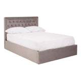 Double bed upholstered in grey velvet with a tufted headboard and a low-profile base, featuring a spacious storage compartment underneath. The bed is dressed with a white mattress and bedding