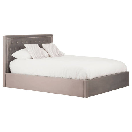 Grey upholstered king bed with a tufted headboard, featuring a low-profile design and two decorative pillows on a white mattress. The bed has a solid base and is positioned on a light-colored floor