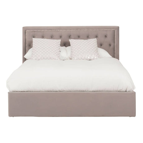 Grey upholstered king bed with a tufted headboard, featuring a plush white comforter and two decorative pillows. The bed has a spacious ottoman base for additional storage