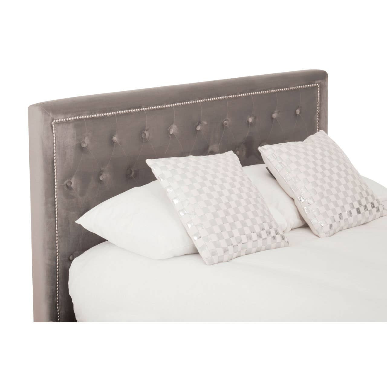 Grey upholstered headboard with button tufting, two white decorative pillows with a subtle pattern, and a white bedspread on a king-sized bed