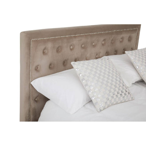 Mink velvet upholstered headboard with tufted detailing, accompanied by two decorative pillows on a white bedspread. The bed is styled in a cozy, inviting manner, showcasing a modern and elegant design