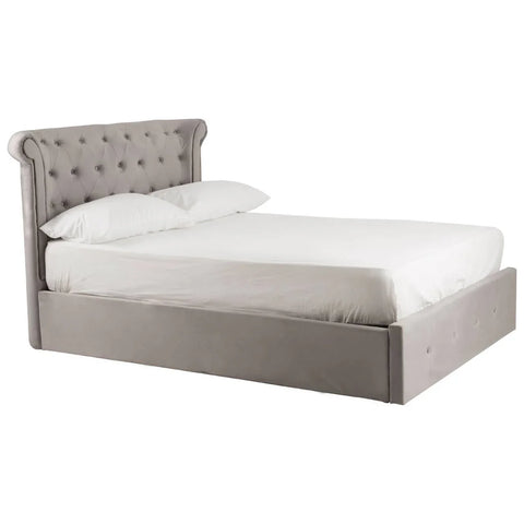 Grey upholstered ottoman bed with button-tufted headboard and white bedding, side angle view
