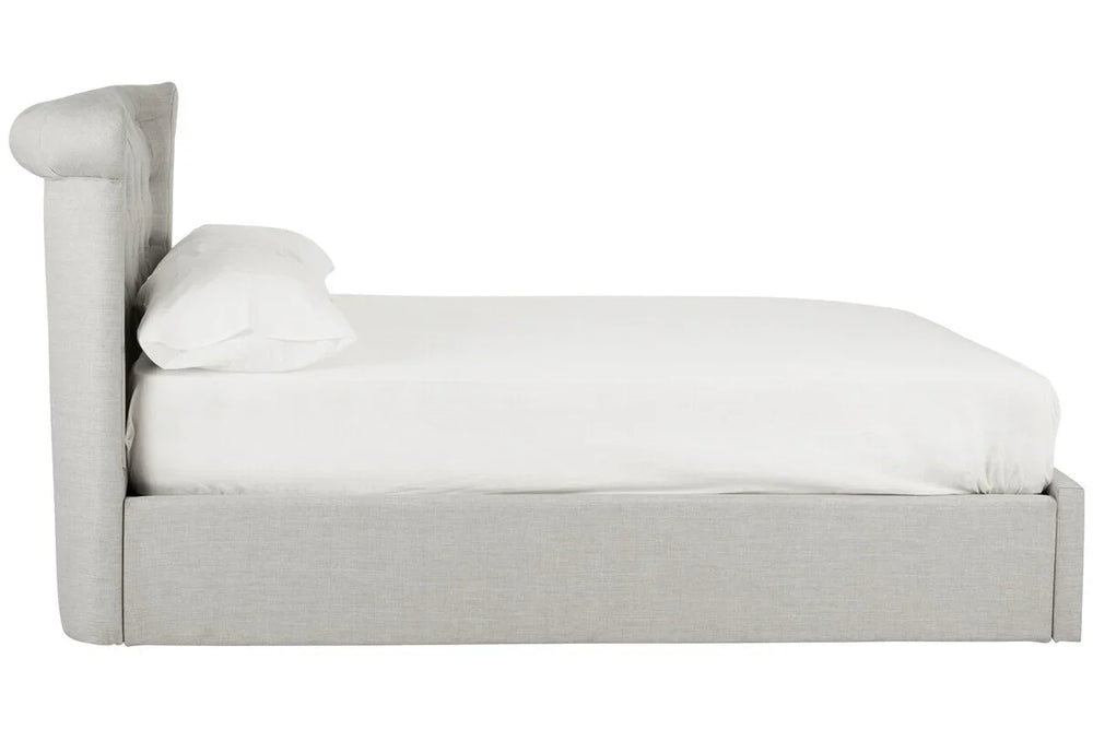 Side view of grey upholstered bed frame with white bedding and pillow
