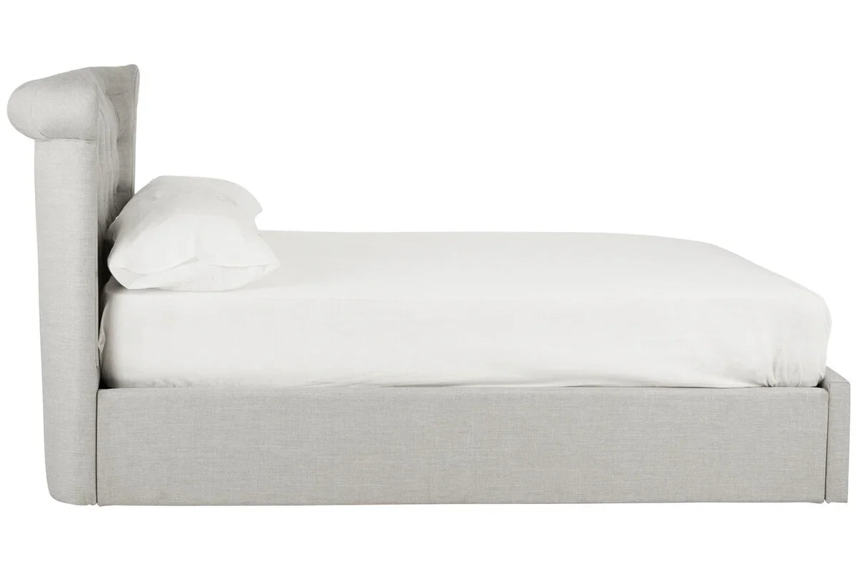 Side view of grey upholstered bed frame with white bedding and pillow