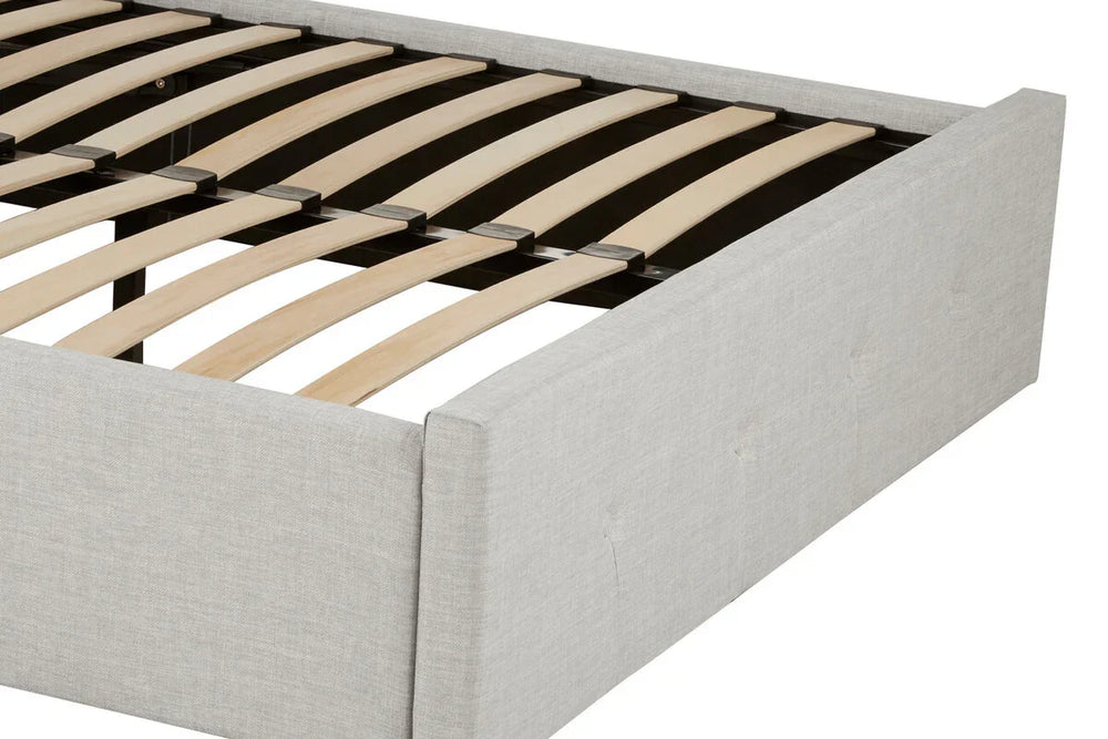 Light grey upholstered bed frame with wooden slats and low padded headboard, close view