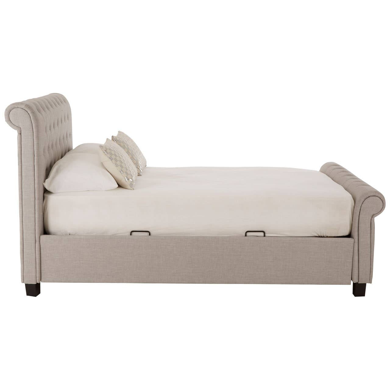 Light grey ottoman double bed with a tufted headboard, featuring a spacious mattress and two decorative cushions. The bed has a sleek design with wooden legs and a storage compartment underneath