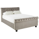 Grey upholstered king bed with a tufted headboard, featuring two decorative pillows and a white mattress, resting on dark wooden legs