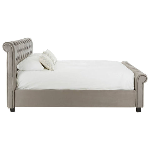 Grey upholstered king bed with a tufted headboard, featuring a low profile and a clean design. The bed is positioned on black legs and includes a white mattress and a decorative pillow