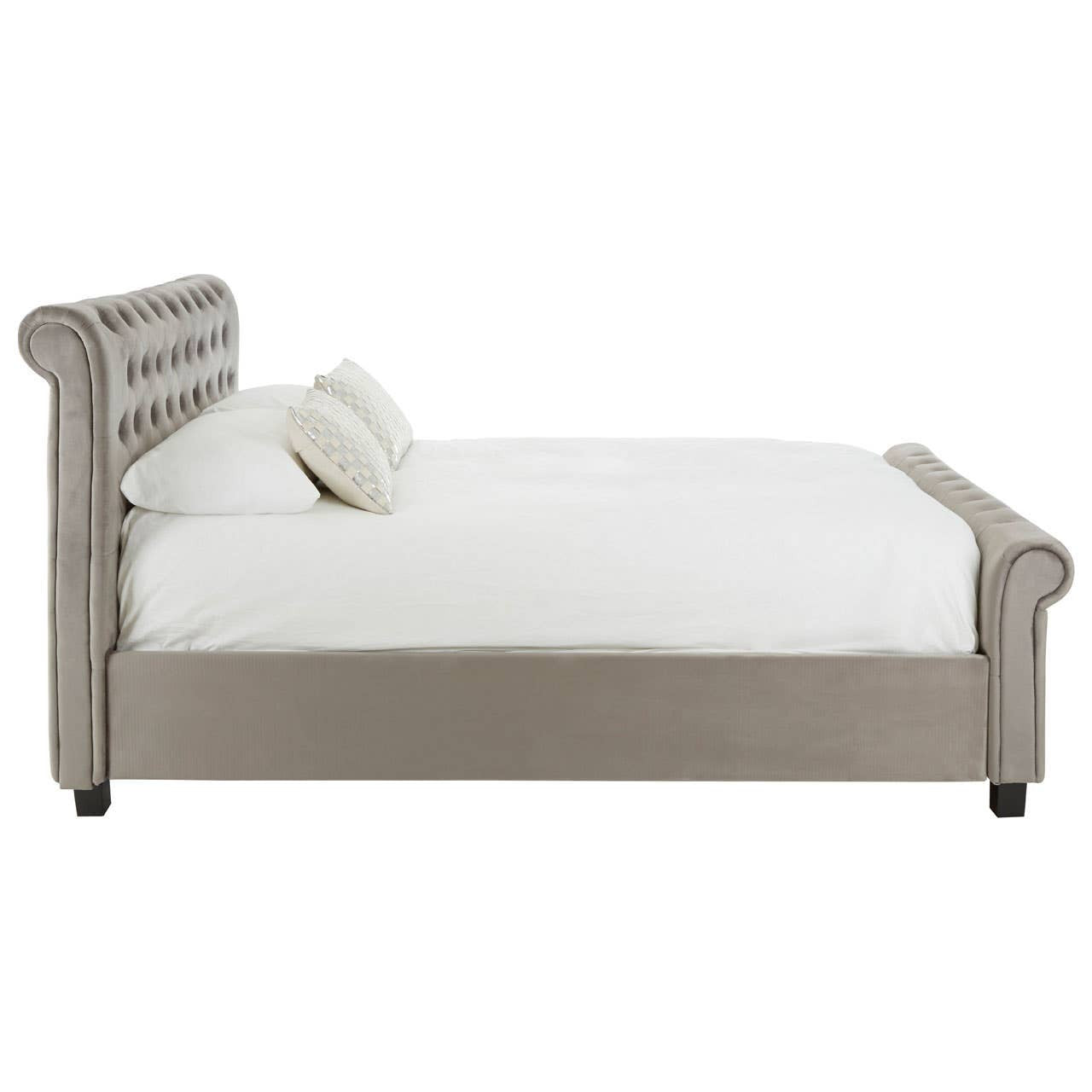 Grey upholstered king bed with a tufted headboard, featuring a low profile and a clean design. The bed is positioned on black legs and includes a white mattress and a decorative pillow