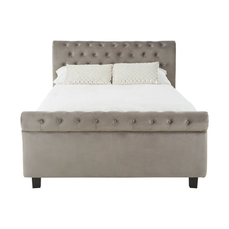 Grey upholstered king bed with a tufted headboard, featuring a padded design and decorative buttons, resting on four black legs. The bed is shown without bedding, highlighting its clean lines and modern aesthetic