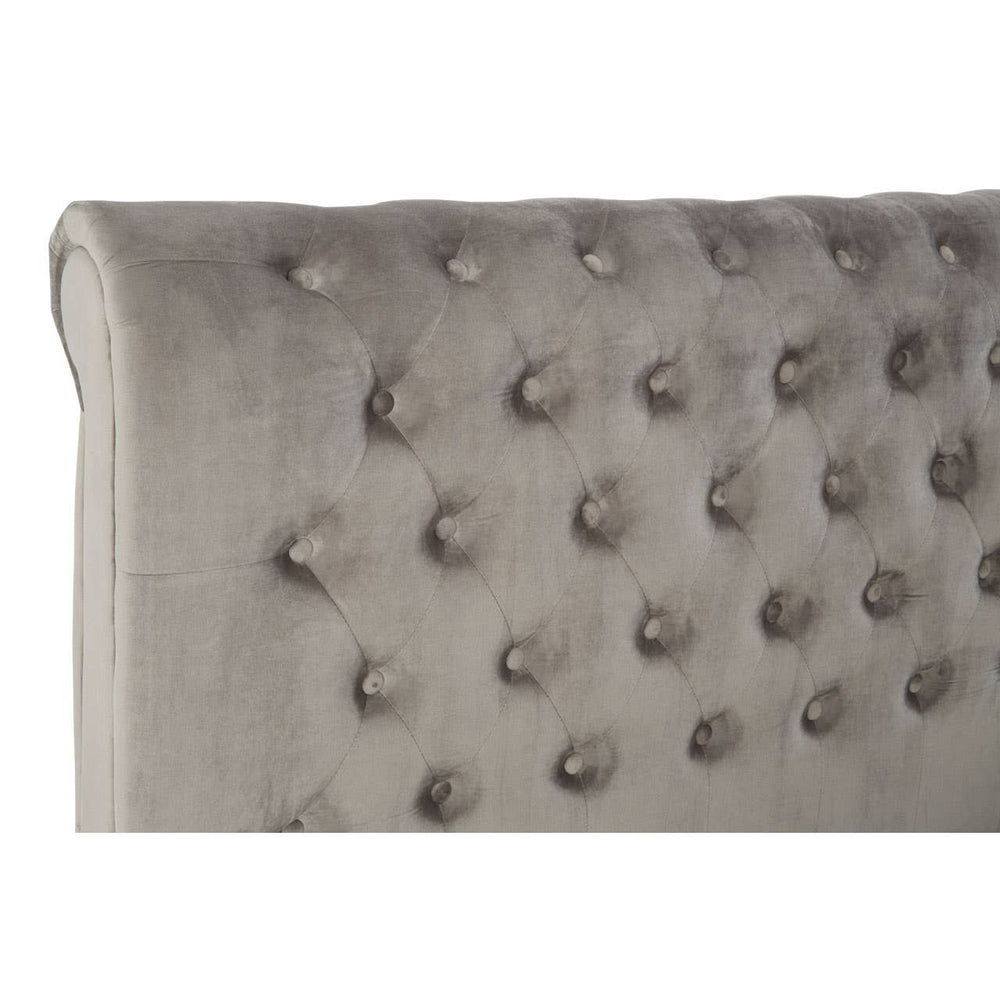 Grey upholstered headboard with tufted detailing and decorative buttons, showcasing a soft fabric texture. The design features a rounded top edge, adding an elegant touch to the overall aesthetic