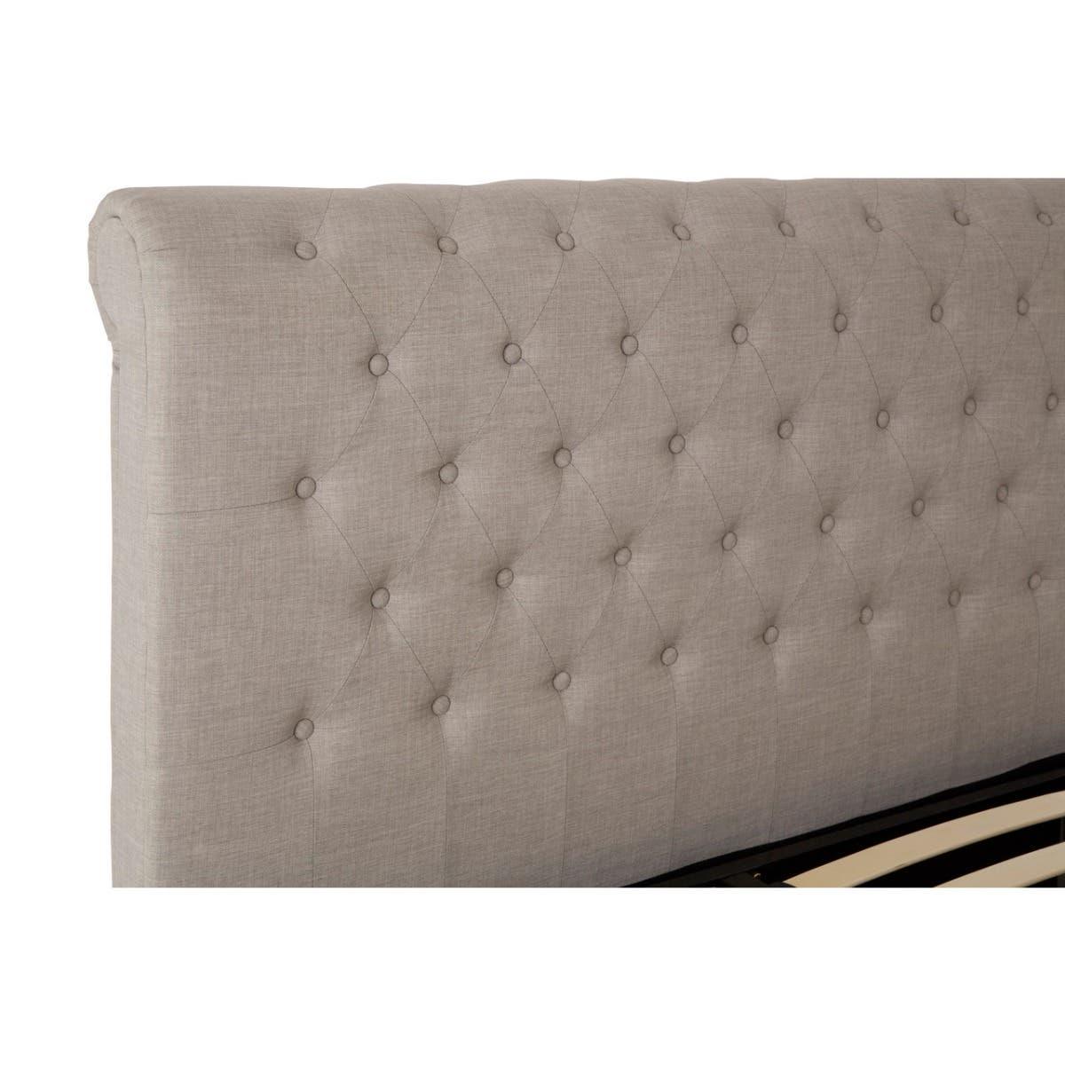 Beige upholstered bed headboard with button-tufted design in close-up view