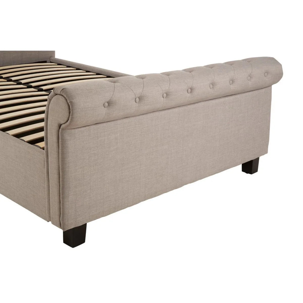 Beige upholstered bed frame with button-tufted footboard and wooden slats, side angle view